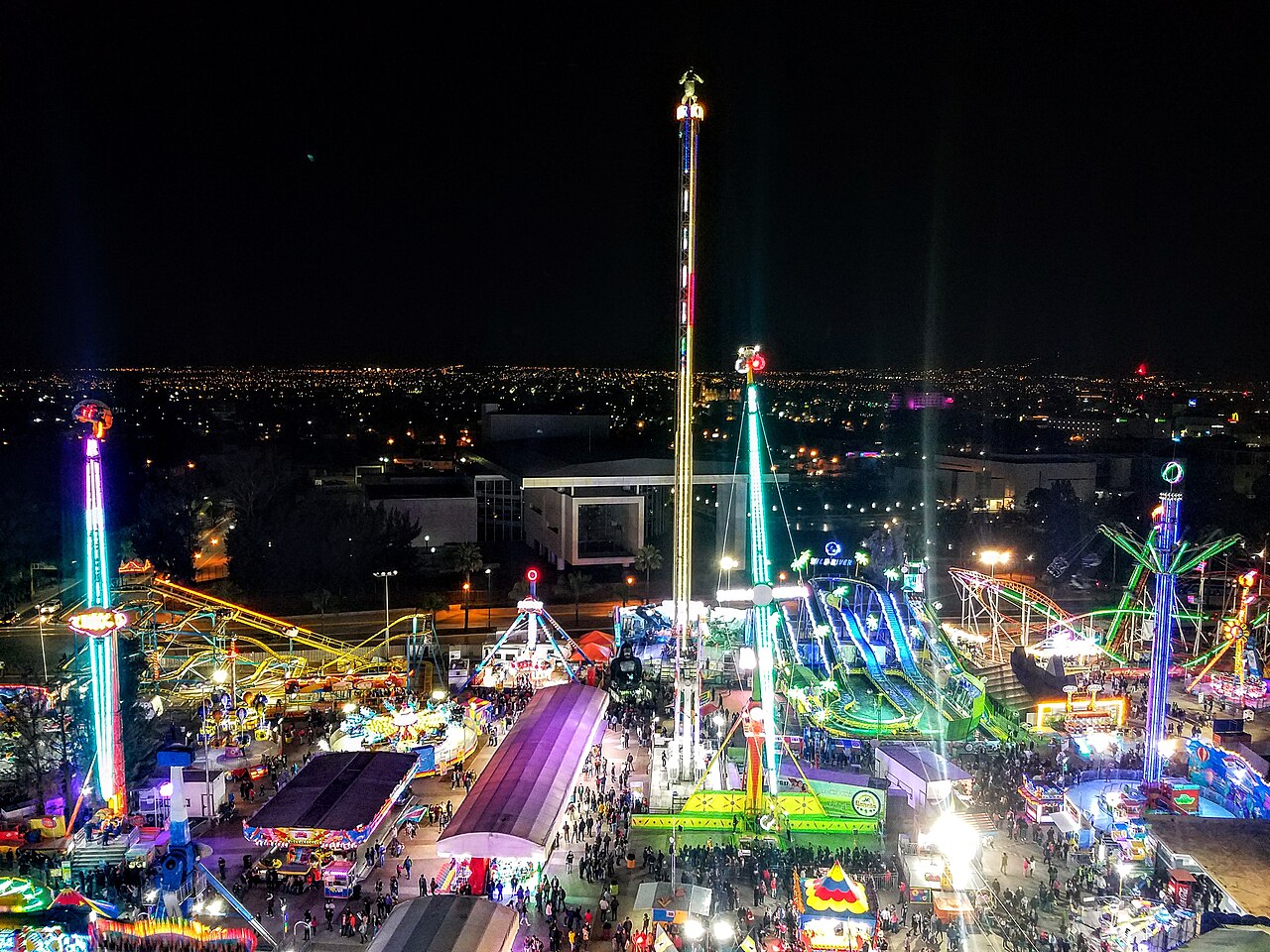 Vista nocturna del área de juegos mecánicos de la Feria de León con atracciones iluminadas